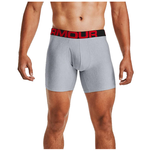 A male torso is wearing gray boxer briefs with a black and red waistband. The individual stands upright, showcasing the fit of the garment. The background is neutral and unobtrusive.