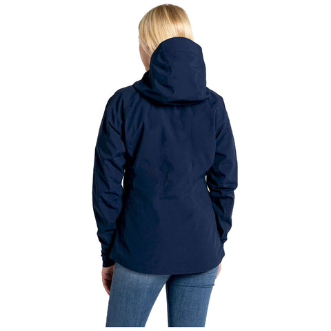 A person wearing a navy blue jacket with a hood faces away, revealing the jacket's back and sleeves while standing relaxed in a simple, unobtrusive background.