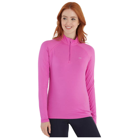 A woman is smiling and wearing a long-sleeve, bright pink athletic top with a half-zip collar in a neutral background, suggesting a casual or sporty setting.