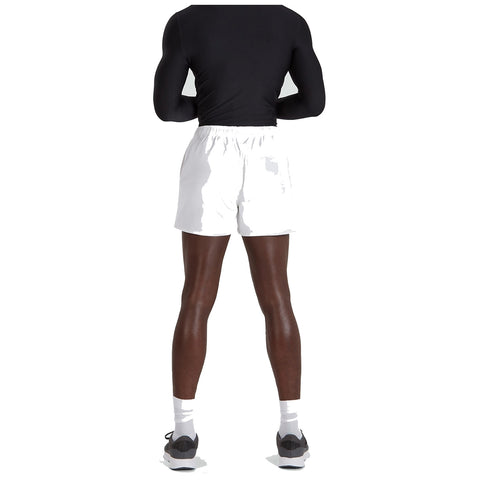 A person is standing with their back facing the viewer wearing a black long-sleeve shirt and white shorts their legs are muscular and they have on black and white athletic shoes