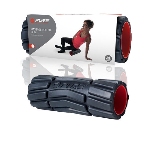 A black and red massage roller lies in front of packaging showing a person using it for muscle relief in a fitness context with a sporty backdrop. The packaging reads "PURE MASSAGE ROLLER FIRM".