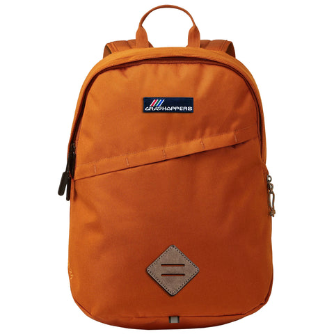 An orange backpack stands upright featuring a front zippered pocket and a top handle while the context shows a plain background emphasizing the backpack's design and color.