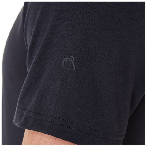 A black t-shirt is displayed with a small logo on the sleeve the fabric appears smooth and fitted suggesting casual wear in a neutral or indoor setting.