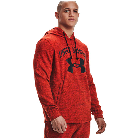 A muscular person wears a red hoodie with black Under Armour branding while standing confidently. The background is plain, emphasizing the subject's focused expression and athletic appearance.