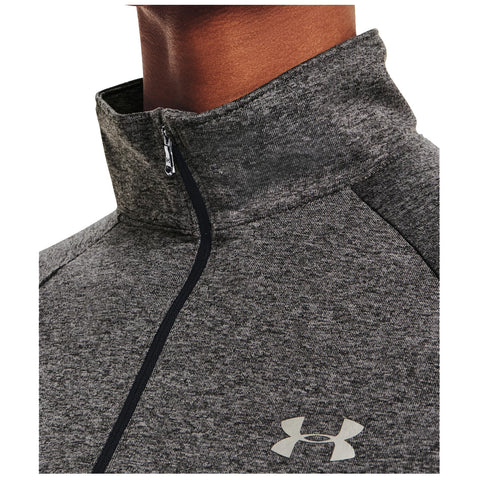 A close-up of a person wearing a high-collared gray athletic zip-up shirt the zipper is partially opened revealing the collar featuring an Under Armour logo prominently displayed on the left side.