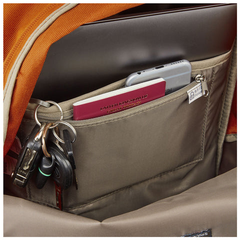 A backpack contains a laptop at the top with a pocket featuring a phone a passport and keys showing organized storage for travel essentials in a cozy environment