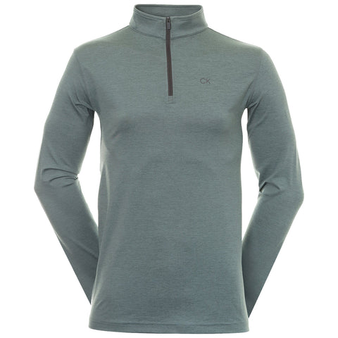 A long-sleeved, zip-neck pullover in a muted green color is displayed against a white background emphasizing its smooth texture and minimalist design featuring a small logo on the chest.