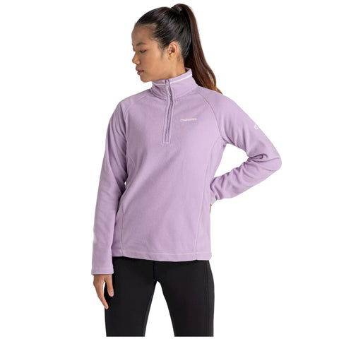 A woman wearing a light purple fleece pullover stands with her head turned slightly to the side, in a neutral background, showcasing a casual outfit suitable for outdoor activities.