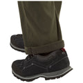 Black outdoor shoes are positioned on the ground with olive green pants resting casually on them in a neutral background showcasing a functional footwear and clothing combination suitable for outdoor activities