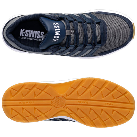 A sports shoe features a navy blue and gray design with multiple laces and a sturdy sole. The outsole is rubber with a tread pattern for traction. The brand label is visible inside.