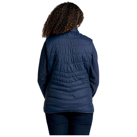 A person is seen from the back wearing a navy blue puffer vest over a long-sleeve top while standing against a plain white background.