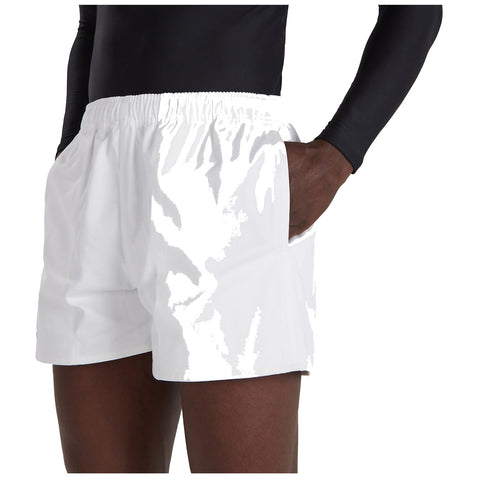 White shorts are being worn by a person with dark skin who is reaching into their pocket while wearing a long-sleeved black top in a neutral background setting.