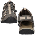 A pair of outdoor sandals features a gray fabric upper with beige straps and a secure lacing system. The sole is rugged, designed for traction on various terrains.