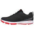 A black athletic shoe with a textured upper features red accents and a white midsole with protruding spikes designed for traction on grass or turf surfaces.