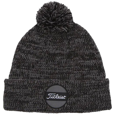 A dark knit beanie with a pom-pom on top is displayed prominently featuring a circular label on the front that reads Titleist suggesting use in cold weather or outdoor activities.