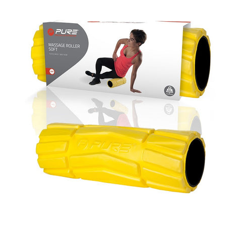 A yellow massage roller lies in the foreground while a person uses it for self-massage in an exercise setting, demonstrating its functionality on a glossy background.