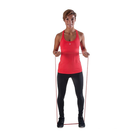 A woman stands upright holding a resistance band with both hands the band is stretched between her hands showing an exercise posture the background is plain white