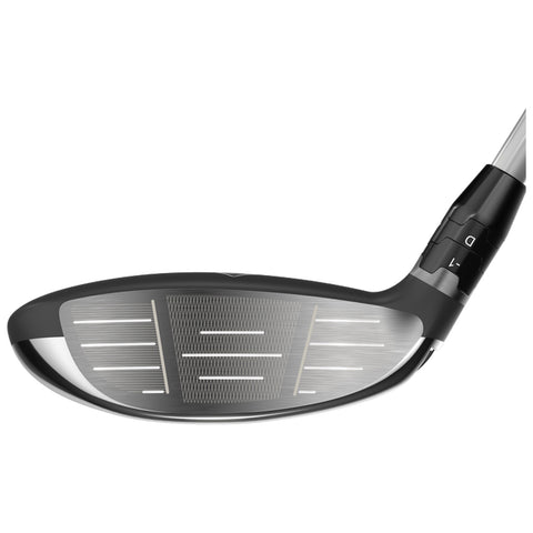 A golf club head is displayed featuring a black and silver design the club face shows grooves and alignment lines indicating its use in swinging a golf ball on a course