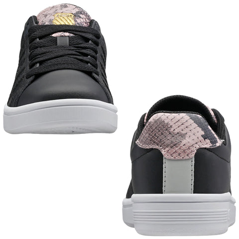 Black sneakers with a textured surface feature laces and a distinctive pink and black patterned heel. They rest on a clean, white surface in a neutral environment.