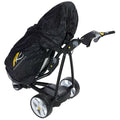 A black golf trolley with a protective cover is positioned upright displaying large wheels and a control handle featuring buttons and a digital display in a neutral setting